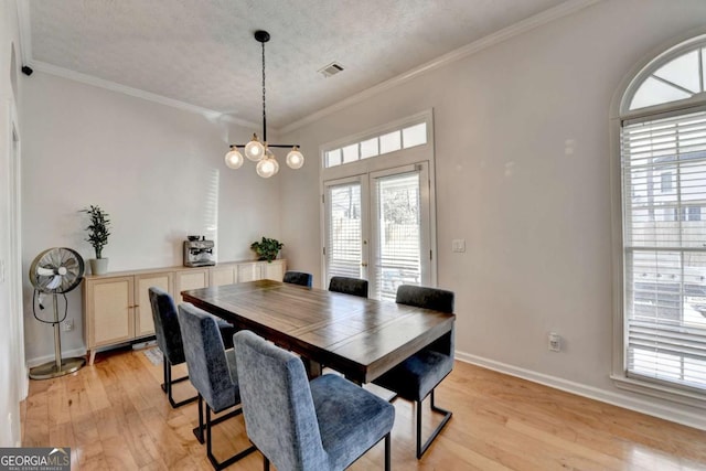 dining space featuring a textured ceiling, a chandelier, crown molding, and light wood-type flooring