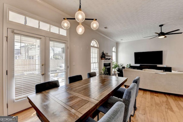 dining room featuring a textured ceiling, a healthy amount of sunlight, crown molding, and light hardwood / wood-style floors