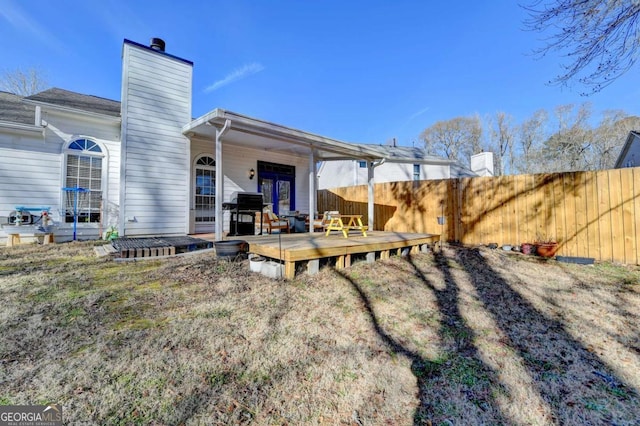 rear view of house featuring a wooden deck and a lawn