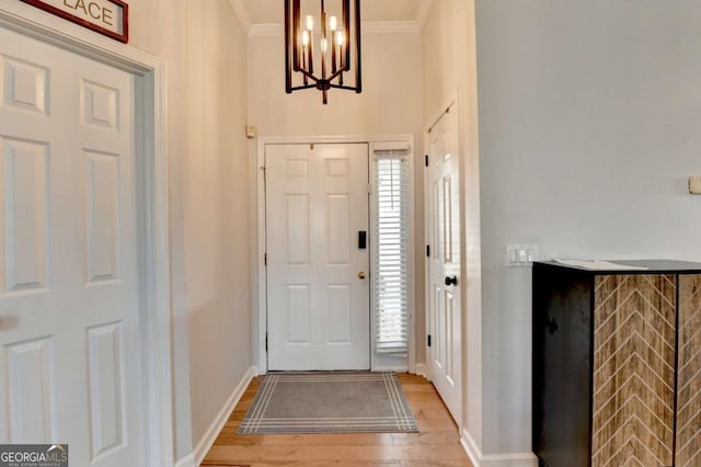 entryway featuring an inviting chandelier, ornamental molding, and hardwood / wood-style floors