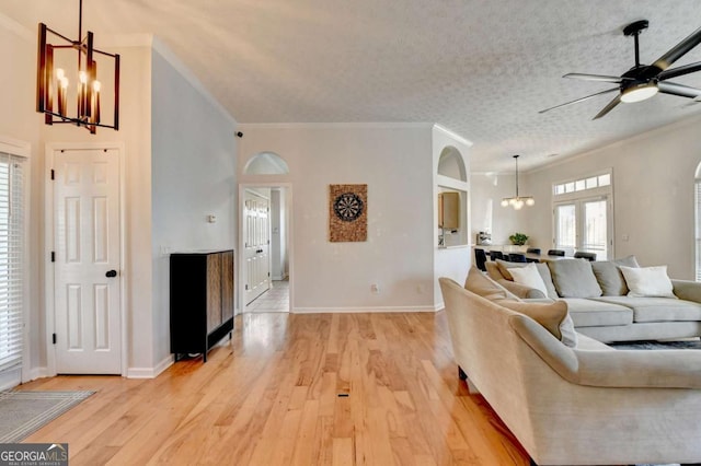 living room featuring a textured ceiling, ceiling fan with notable chandelier, crown molding, and light hardwood / wood-style floors