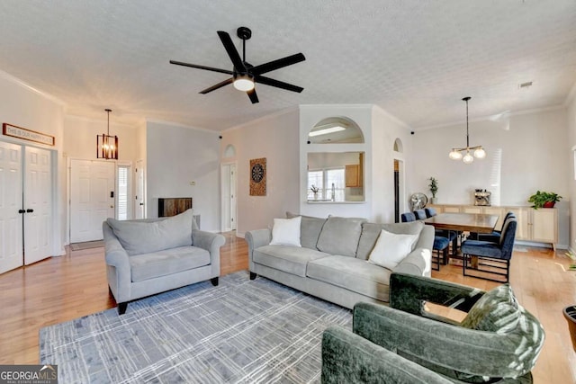 living room with ceiling fan with notable chandelier, a textured ceiling, crown molding, and hardwood / wood-style floors