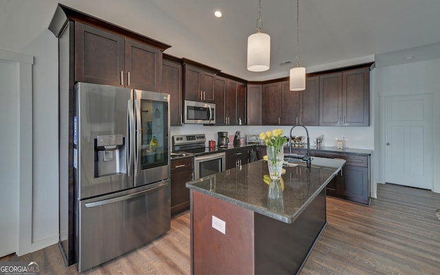 kitchen with decorative light fixtures, dark stone counters, stainless steel appliances, and dark brown cabinetry