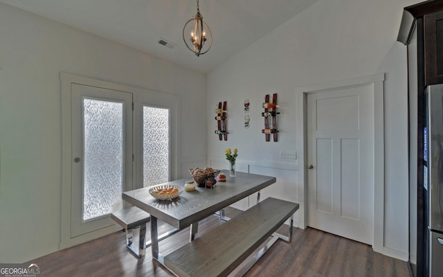 dining space with dark wood-type flooring, lofted ceiling, and a notable chandelier