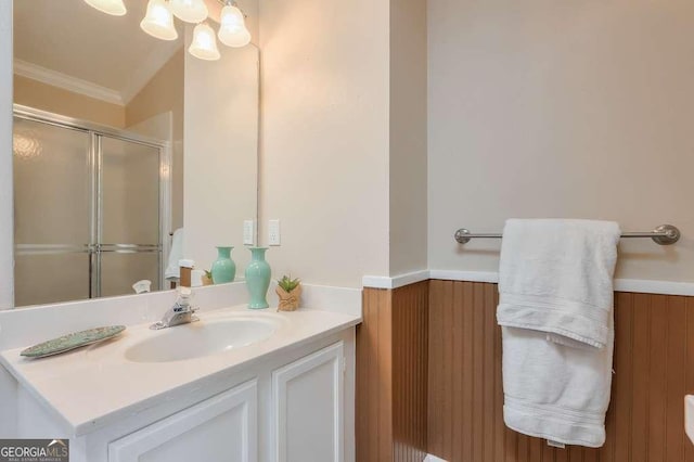 bathroom featuring wood walls, vanity, crown molding, and a shower with door