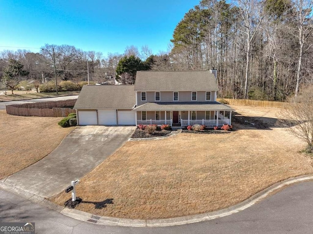 view of front of house featuring covered porch, a front yard, and a garage