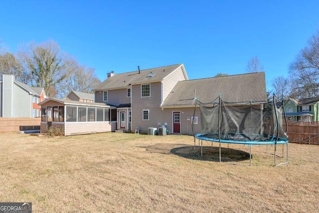 back of property featuring a sunroom, a yard, and a trampoline