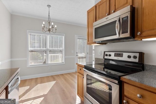 kitchen featuring appliances with stainless steel finishes, a notable chandelier, hanging light fixtures, ornamental molding, and light hardwood / wood-style flooring