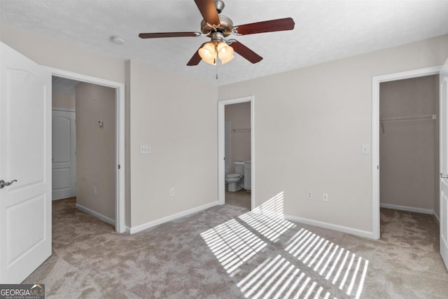 unfurnished bedroom with a spacious closet, ceiling fan, a closet, and light colored carpet