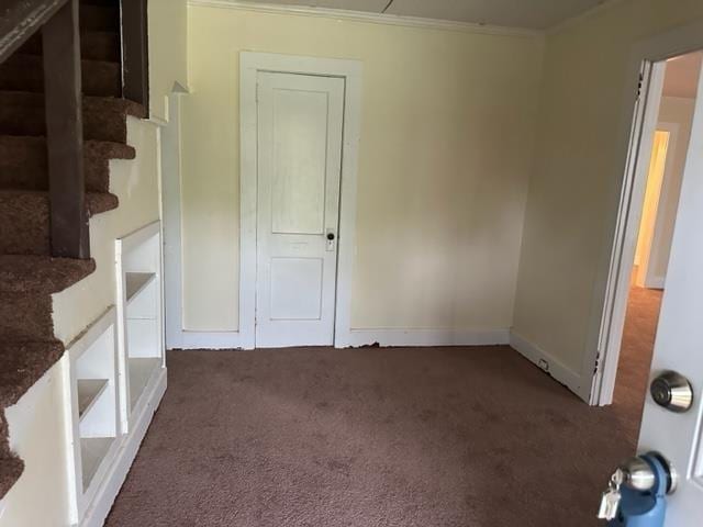 empty room featuring dark carpet and ornamental molding