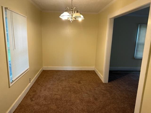 unfurnished room with a textured ceiling, crown molding, a chandelier, and dark colored carpet