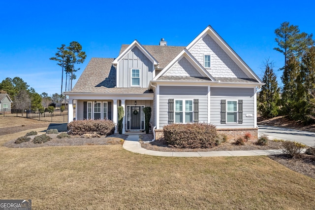 craftsman inspired home featuring a front yard, roof with shingles, fence, and a chimney