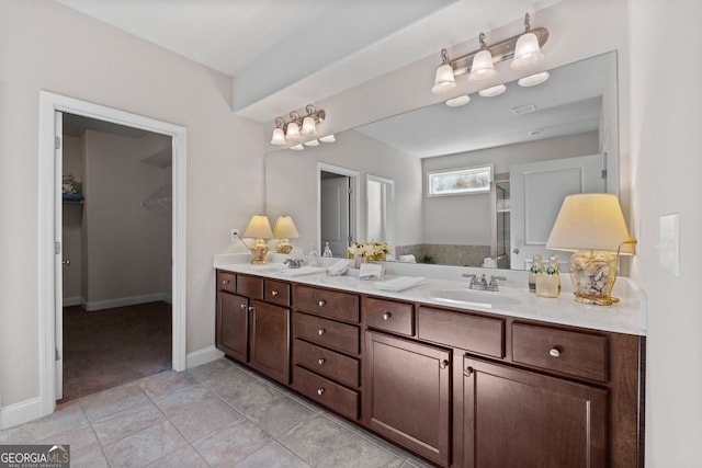 full bath featuring double vanity, baseboards, and a sink