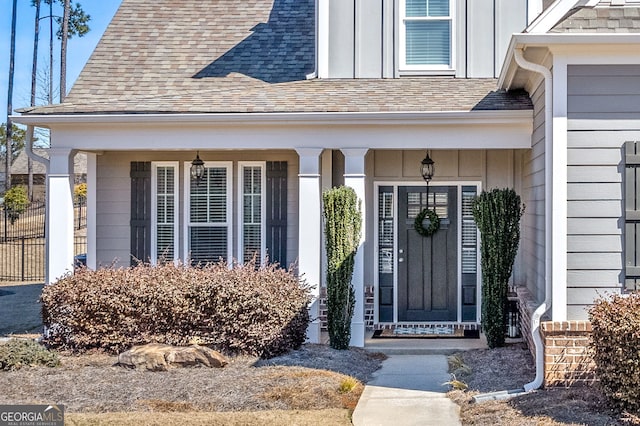 entrance to property featuring covered porch, roof with shingles, and board and batten siding