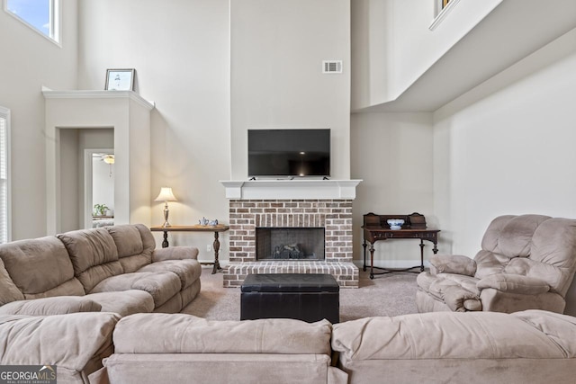 living room with a brick fireplace, ceiling fan, and a towering ceiling