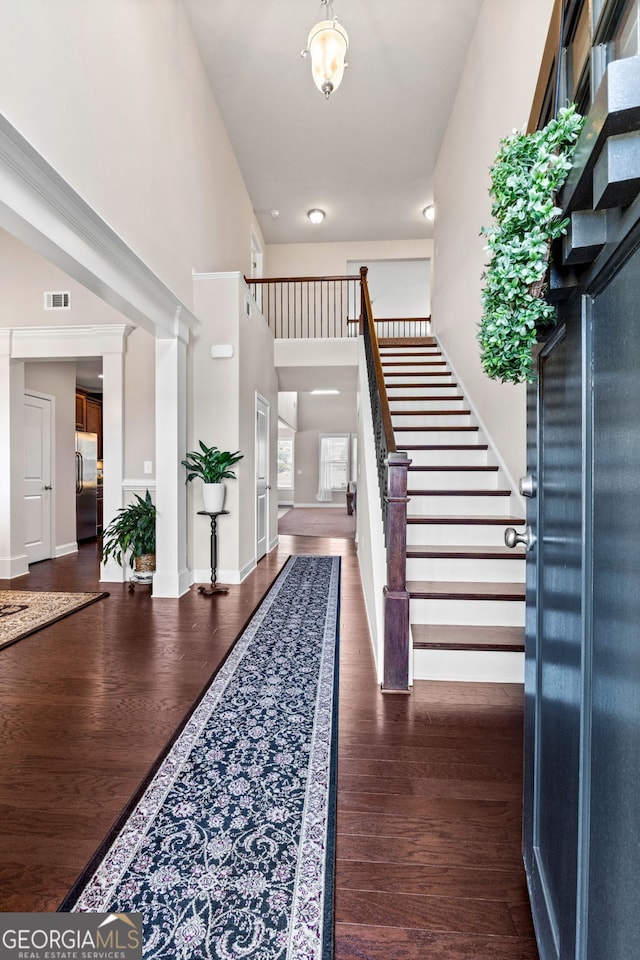 entryway featuring baseboards, visible vents, dark wood-style flooring, a high ceiling, and stairs