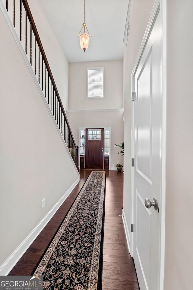 entryway with dark wood-style flooring, visible vents, a towering ceiling, stairway, and baseboards