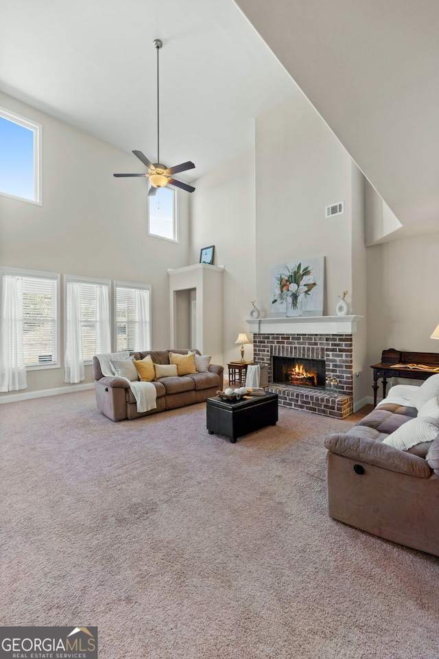 living area featuring plenty of natural light, ceiling fan, carpet, and a fireplace