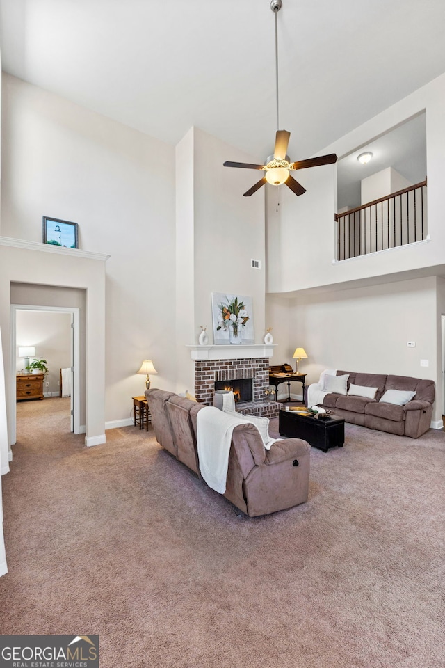 carpeted living area with a high ceiling, a brick fireplace, a ceiling fan, and baseboards