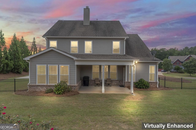 back house at dusk with a patio area and a yard