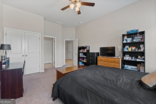 bedroom with a ceiling fan, a closet, light colored carpet, and baseboards