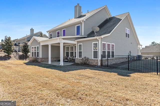 back of property featuring brick siding, fence, a lawn, and a patio