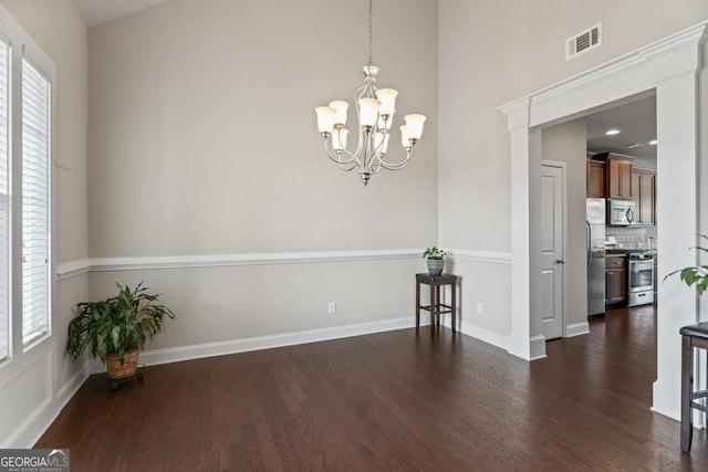 empty room featuring an inviting chandelier, dark hardwood / wood-style flooring, and a healthy amount of sunlight