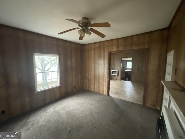 empty room featuring ceiling fan and wooden walls