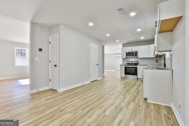 kitchen with backsplash, sink, light hardwood / wood-style flooring, stainless steel appliances, and white cabinets