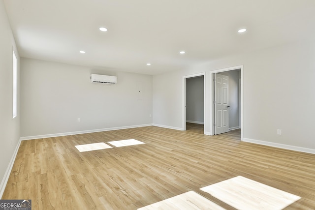 empty room with a wall mounted AC and light wood-type flooring