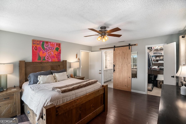 bedroom featuring ensuite bathroom, a barn door, ceiling fan, a walk in closet, and a closet