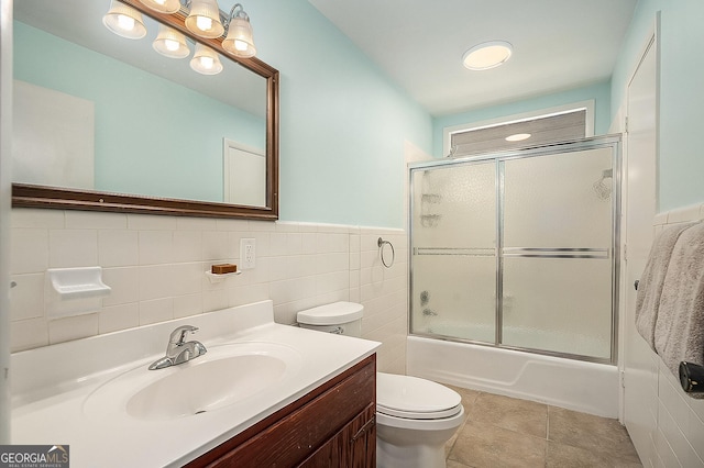 full bathroom with toilet, vanity, tile walls, tile patterned flooring, and combined bath / shower with glass door