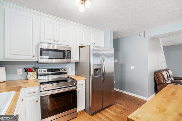 kitchen featuring white cabinetry, butcher block counters, and appliances with stainless steel finishes