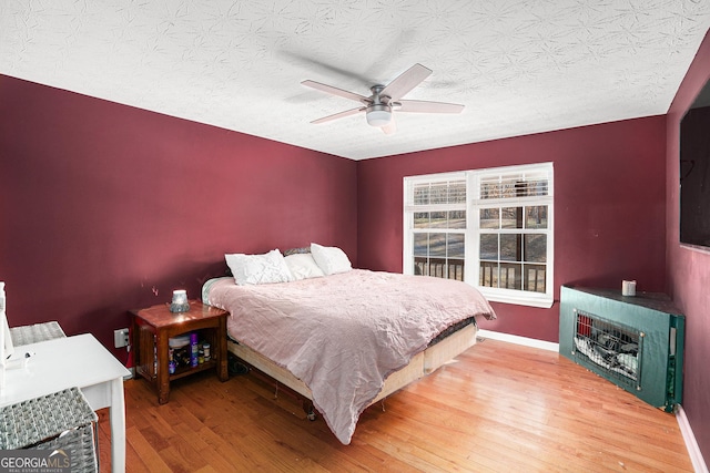 bedroom with hardwood / wood-style flooring, a textured ceiling, and ceiling fan