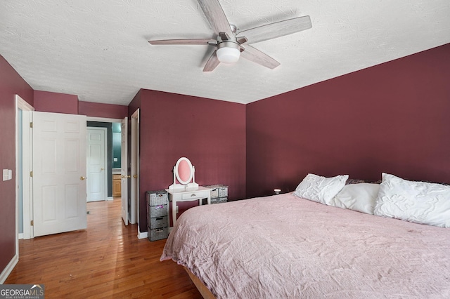 bedroom with ceiling fan, hardwood / wood-style floors, and a textured ceiling