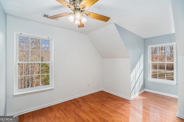 additional living space with lofted ceiling, a textured ceiling, ceiling fan, and light wood-type flooring