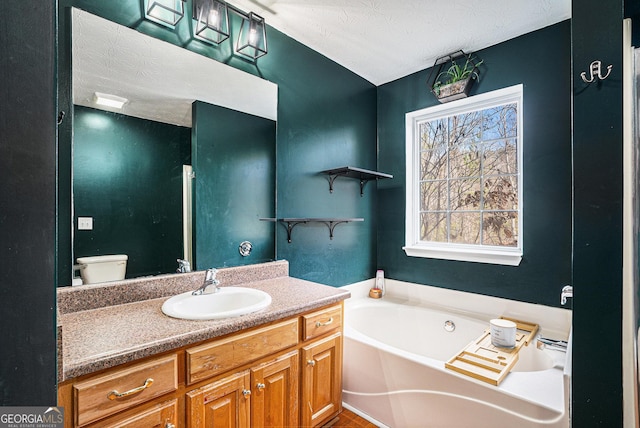 bathroom featuring vanity, toilet, a textured ceiling, and a tub