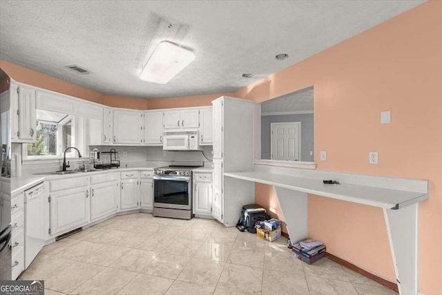 kitchen featuring sink, white appliances, white cabinetry, and a textured ceiling