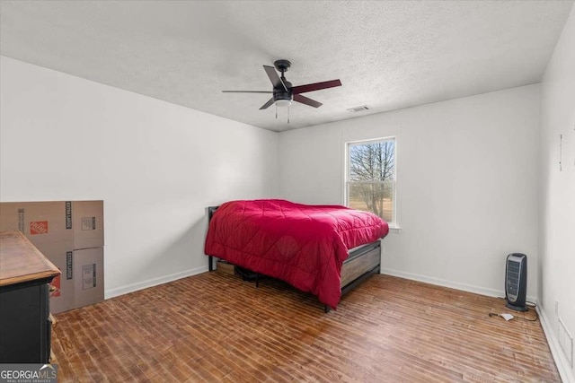 bedroom featuring a textured ceiling, ceiling fan, and wood-type flooring