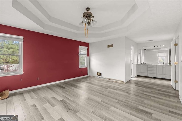 interior space featuring ceiling fan, light hardwood / wood-style flooring, and a tray ceiling