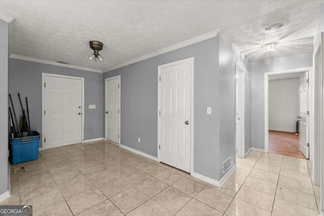 tiled entrance foyer featuring a textured ceiling and ornamental molding