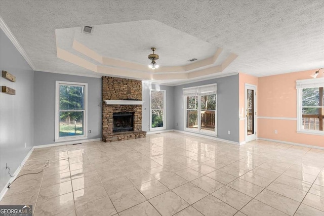 unfurnished living room featuring a stone fireplace, a healthy amount of sunlight, and a tray ceiling