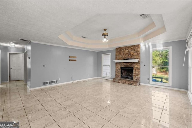 unfurnished living room with a textured ceiling, a tray ceiling, ornamental molding, and a fireplace