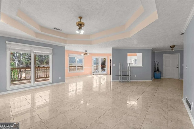 unfurnished living room with a textured ceiling, a tray ceiling, and a notable chandelier