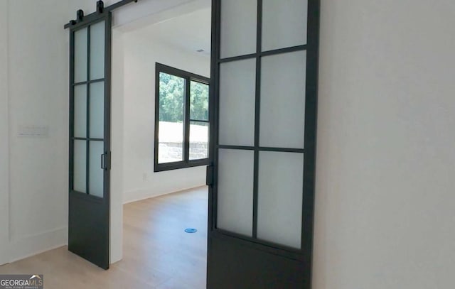 hall with light hardwood / wood-style floors and a barn door