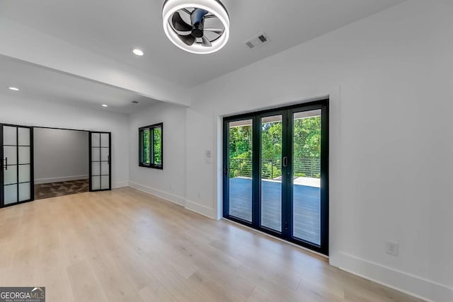 spare room with french doors and light hardwood / wood-style floors