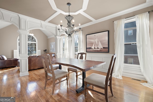 dining area with ornate columns, a chandelier, coffered ceiling, light hardwood / wood-style floors, and crown molding