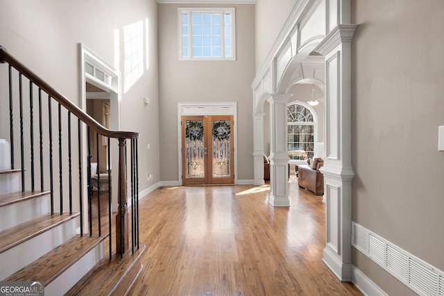 entryway featuring decorative columns, a healthy amount of sunlight, light hardwood / wood-style floors, and french doors