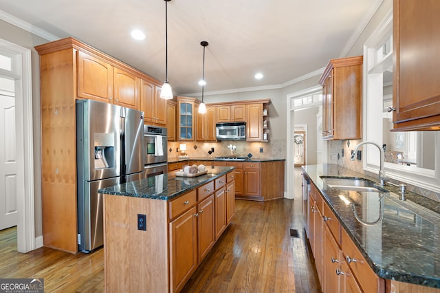 kitchen featuring sink, dark stone countertops, hanging light fixtures, a center island, and stainless steel appliances