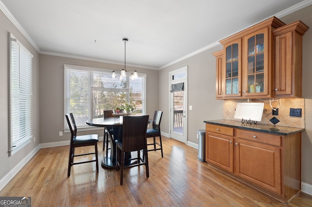 dining area with crown molding, a chandelier, and light hardwood / wood-style flooring